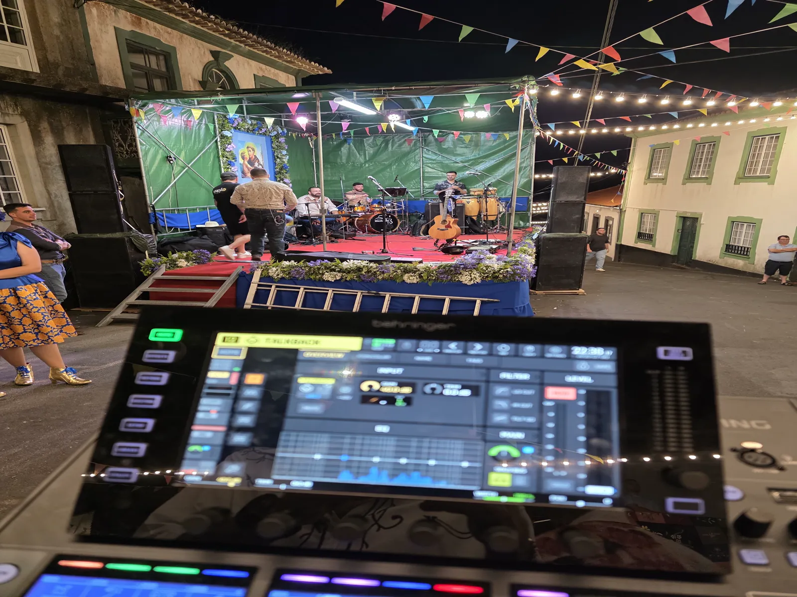 Vista do palco iluminado e público a partir da mesa de som no concerto ao ar livre na Serra da Ribeirinha.